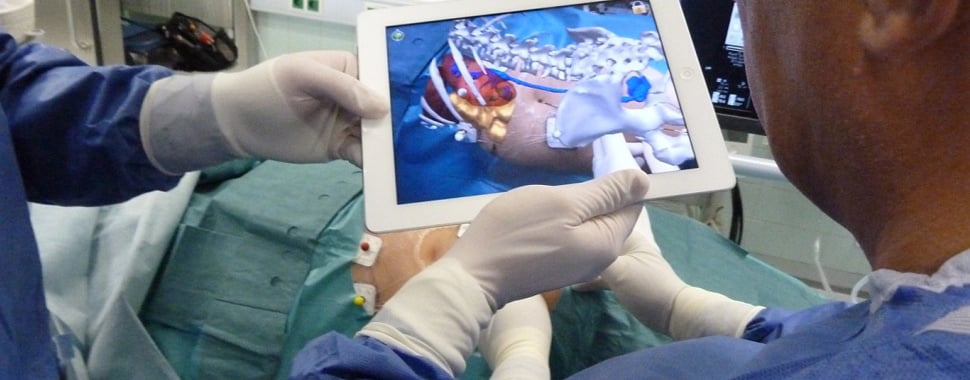 Surgeons using an augmented reality (AR) application on a tablet during a medical procedure. The AR interface provides a detailed, 3D visualization of the patient’s internal anatomy.